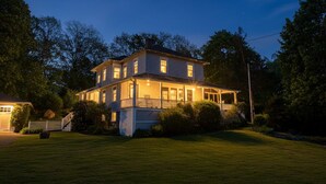 Een twee verdiepingen tellend huis met een veranda en een verzorgd gazon.