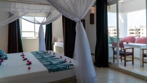 Une chambre d’hôtel avec un lit, un balcon avec des chaises et une vue sur les immeubles.