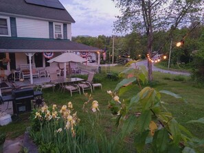 A house with a porch, outdoor seating, and a garden with yellow flowers.
