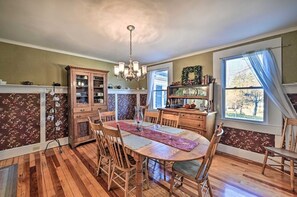 A dining room with a wooden table and chairs, a chandelier, and a window with curtains. - 10 Mi To Gore Mountain: Home In Adirondack Park 5 Bedroom Home (Olmstedville)