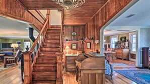 A spacious living room with a wooden staircase, a fireplace, and a dining area. - 10 Mi To Gore Mountain: Home In Adirondack Park 5 Bedroom Home (Olmstedville)