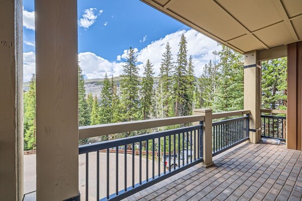 A wooden deck with a railing overlooking a forested area with mountains in the background. - Lone Eagle 3013 3 Bedroom Condo (Keystone)