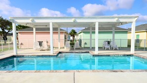 A swimming pool with a covered area and lounge chairs.