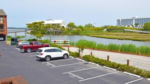 Un parking avec des places délimitées, une étendue d’eau et un pont en arrière-plan.