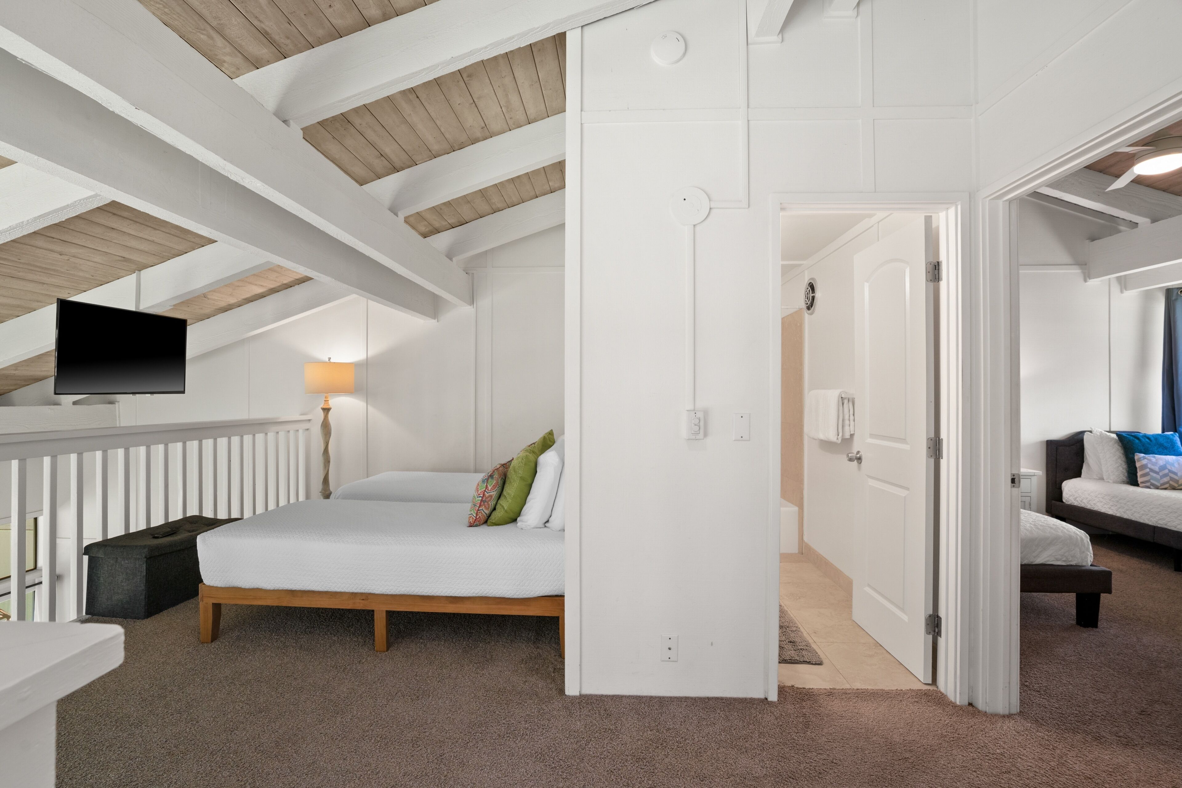 Ein Schlafzimmer mit Bett, Fernseher, Schreibtisch und begehbarem Kleiderschrank.