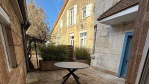 A courtyard with a round table, stone flooring, and a blue door.