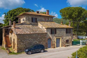 A stone building with a tiled roof, a car parked in front, and a staircase leading to the entrance. - Borgo Panicale Apartments (Panicale)