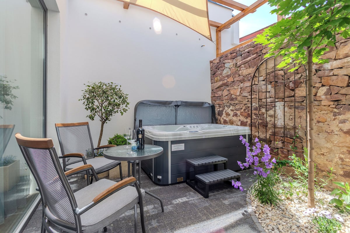 Un'area patio con vasca idromassaggio, posti a sedere e un muro in pietra.