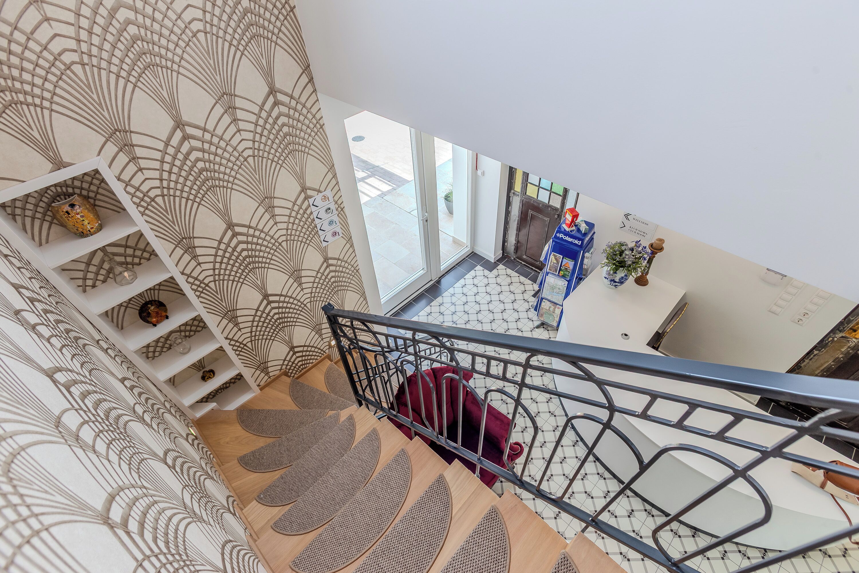 A modern interior with a staircase, patterned wallpaper, and a view of the outside.