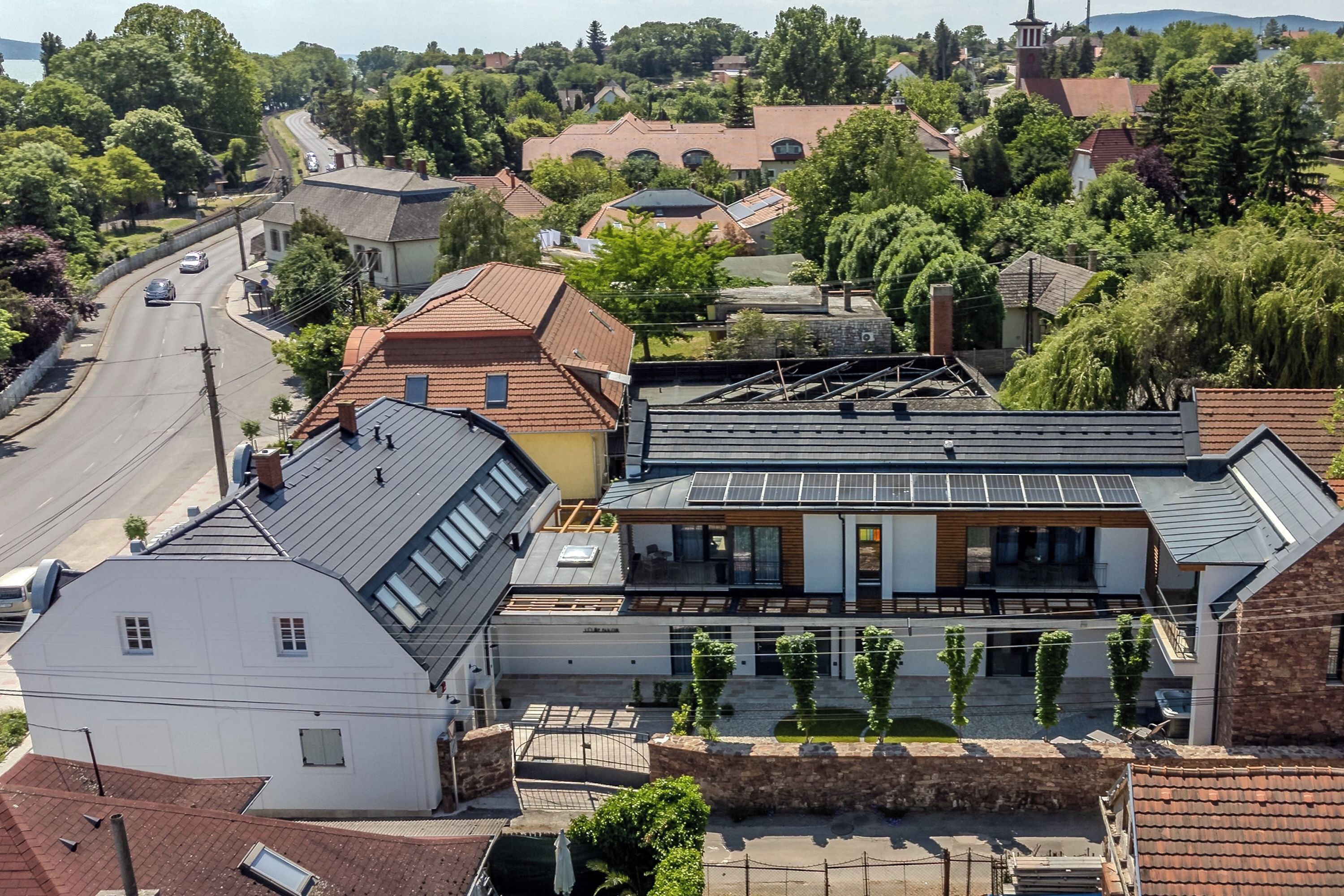 A modern building with a sloped roof, solar panels, and a courtyard with trees.