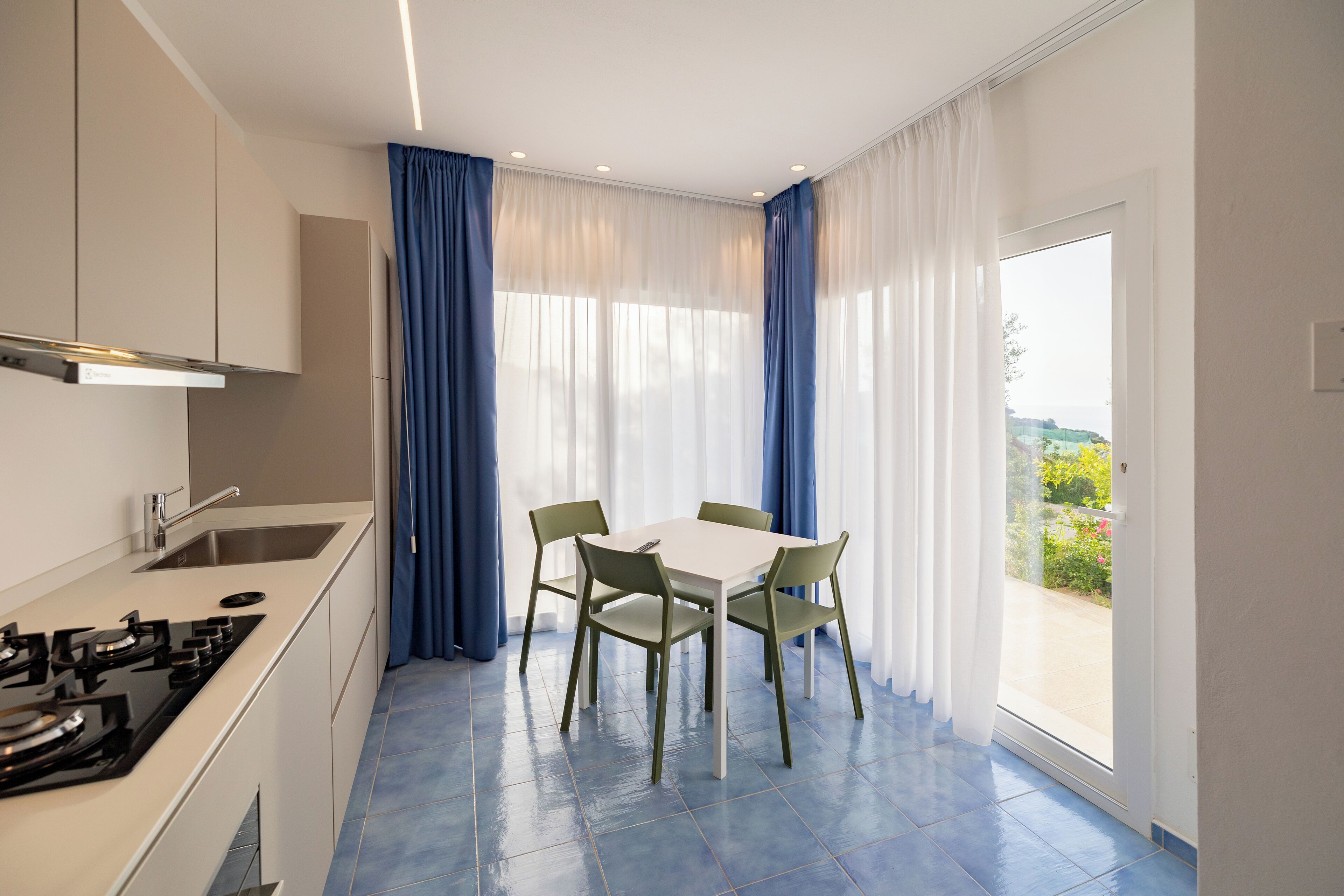 A modern kitchen with a gas stove, a sink, and a dining area with a table and chairs.