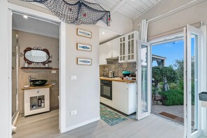 A modern kitchen with white cabinets, a large window, and a view of the garden.