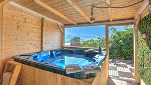 A wooden cabin with a hot tub, wooden walls, and a view of mountains and greenery. - Casa Fra Gli Ulivi (Ameglia)