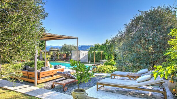 A poolside area with a wooden pergola, lounge chairs, and a small table. - Casa Fra Gli Ulivi (Ameglia)