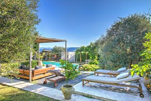 Un espace aménagé au bord de la piscine, avec une pergola en bois, des chaises longues et une petite table.