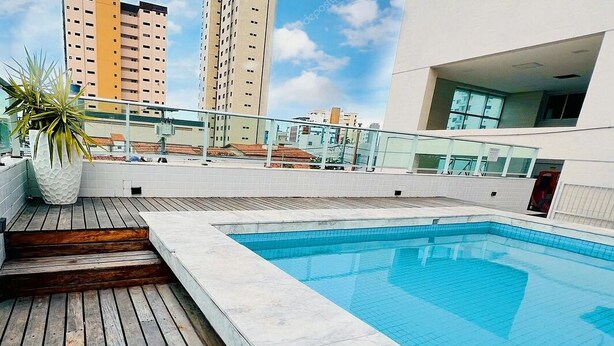 A rooftop swimming pool with a wooden deck and a potted plant. - Tambaú Flex Home - LikeHome Hospedagens (João Pessoa)