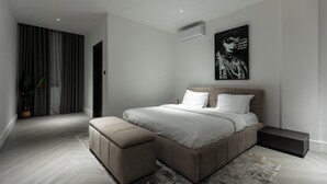 Un dormitorio moderno con una cama grande, una mesita de noche y un aire acondicionado de pared.