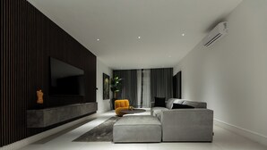 Una sala de estar moderna con un sofá modular, un sillón amarillo y un televisor de pantalla plana montado en la pared.