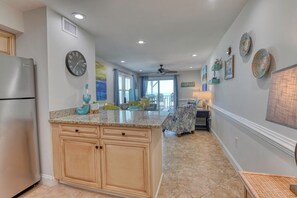 Una cocina con una isla central, armarios de madera, un refrigerador y un comedor con sillas y una mesa.