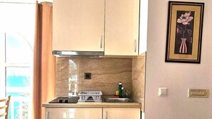Une cuisine de taille réduite, avec des meubles de couleur claire, une cuisinière encastrée et un petit plan de travail.