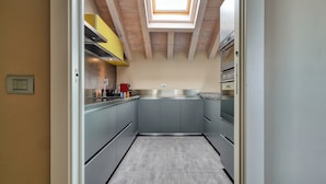 Une cuisine étroite avec des meubles gris, un puits de lumière et une vue sur la pièce adjacente.
