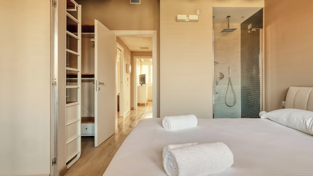 Une chambre d’hôtel comprenant un lit, un dressing et un espace douche.