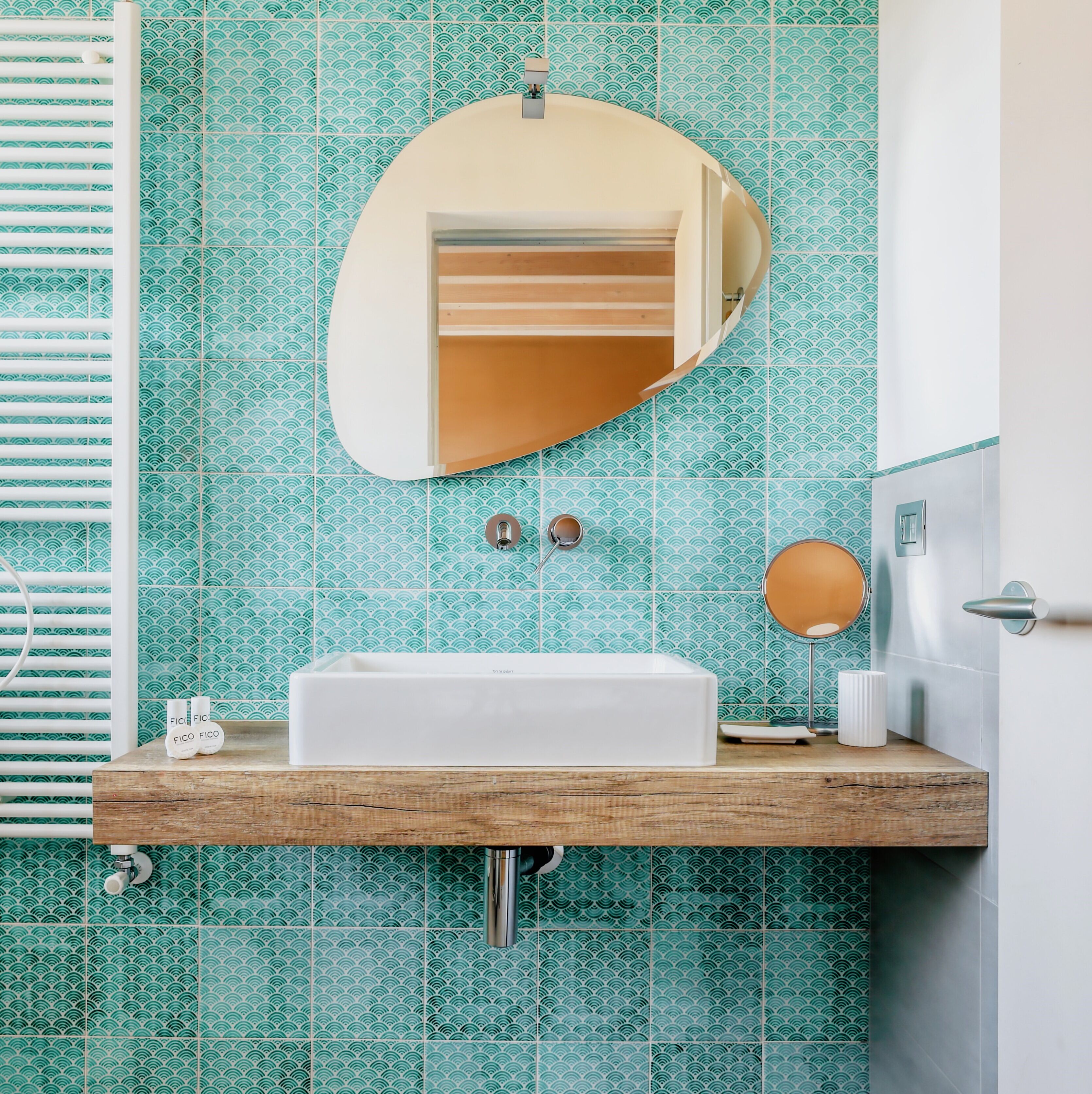 Un bagno con un lavandino bianco, uno specchio e un portascopevoli.