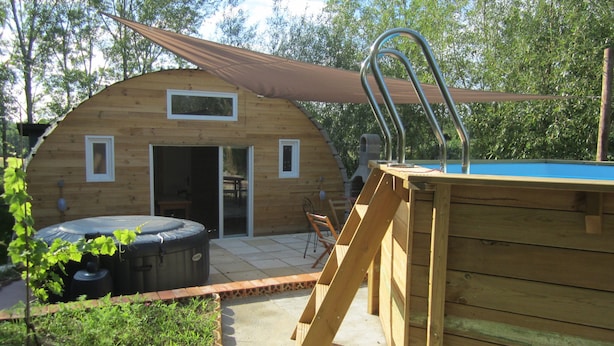 A wooden cabin with a pool, a hot tub, and a covered patio area.