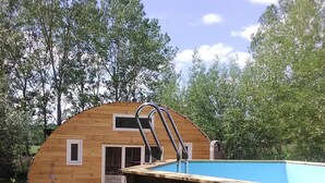 A wooden structure with a pool, a door, and a window.