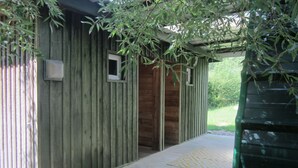 A wooden building with a covered entrance, a small window, and a green hose on the right.
