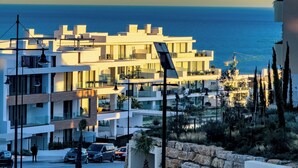 A modern building with a flat roof, large windows, and a view of the sea.