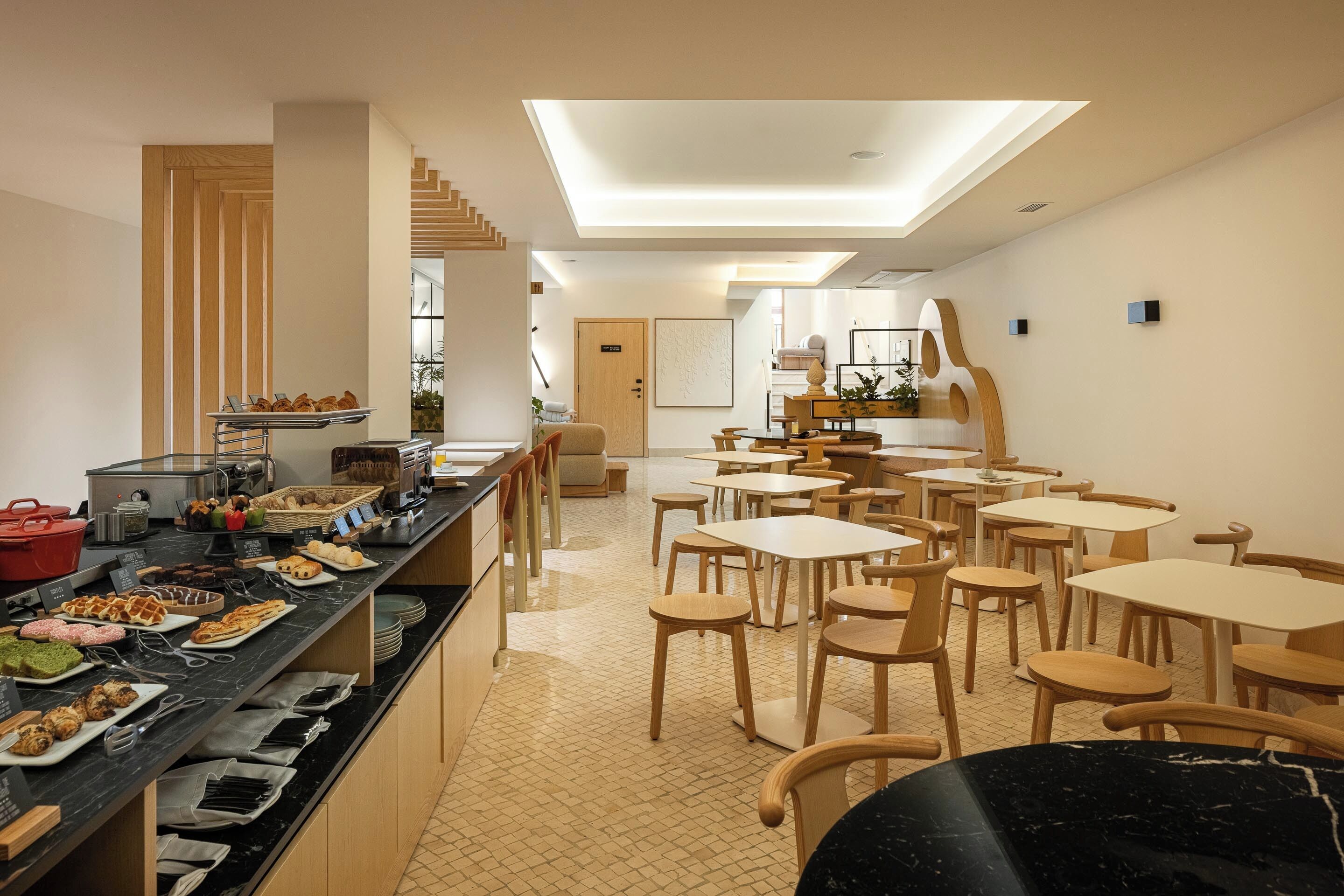 A modern dining area with a long counter, multiple tables, and chairs.
