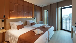 Ein Hotelzimmer mit einem großen Bett, einem Schreibtisch und Blick auf die Stadt durch das Fenster.