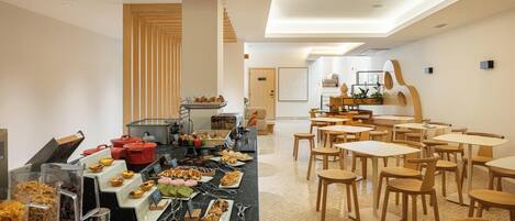 A dining area with a buffet setup, wooden chairs, and tables.
