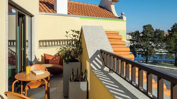 Un balcon avec une table et des chaises, un escalier et une vue sur la mer.