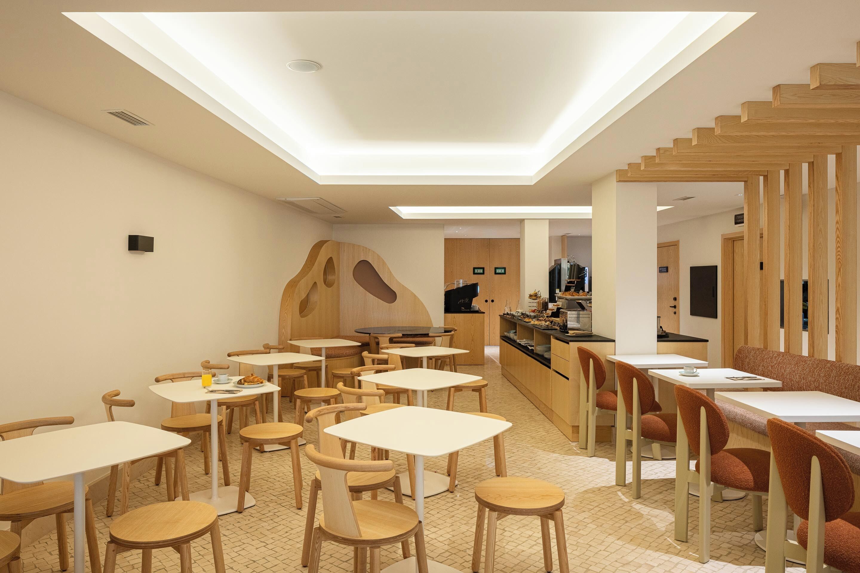 A modern interior with tables and chairs, a wooden accent wall, and a skylight.