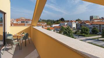 Balcón con mesa y sillas, vista a una zona residencial con casas y cielo despejado.