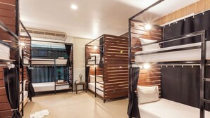 Ein Hotelzimmer mit Stockbetten, einem kleinen Tisch mit einer Vase und einem Fenster mit Vorhängen.