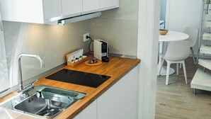 Une cuisine moderne dotée d’un plan de travail en bois, d’un évier en acier inoxydable et d’un lave-linge encastré.