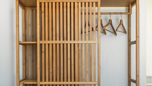 Une armoire en bois, dotée de plusieurs étagères et d’un espace pour suspendre les vêtements, placée contre un mur uni.