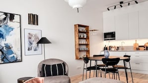 A modern living room with a sofa, ottoman, and a dining area with chairs and a table. - Stylish Luxe home by the water (Stockholms län)