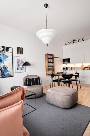 A modern living room with a sofa, ottoman, and a dining area with chairs and a table.