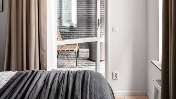A bedroom with a bed, a window with curtains, a radiator, and a door leading to a balcony. - Stylish Luxe home by the water (Stockholms län)