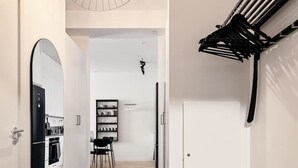 A hallway with a mirror, a hanging light fixture, a coat rack, and a door leading to a kitchen area. - Stylish Luxe home by the water (Stockholms län)