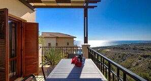 A balcony with a table, chairs, and a bottle of champagne.