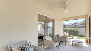 Un patio moderne comprenant un canapé, des fauteuils et une table, avec une porte-fenêtre coulissante donnant sur un jardin.