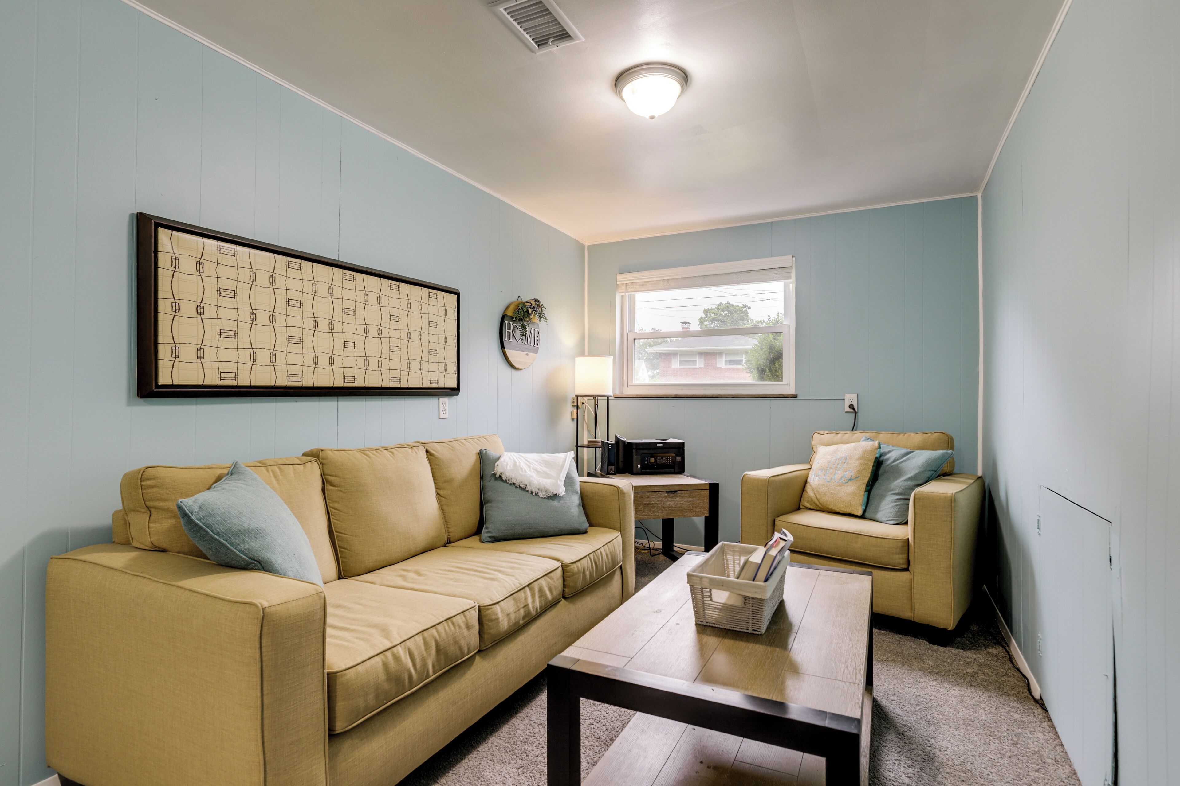 A living room with a beige sofa, a coffee table, and a small side table with a lamp.