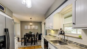 A compact kitchen with white cabinets, a granite countertop, a built-in sink, and a dining area with a table and chairs. - 10 Mi to Dtwn Cincinnati: Home w/ Patio & Yard! (Cincinnati)