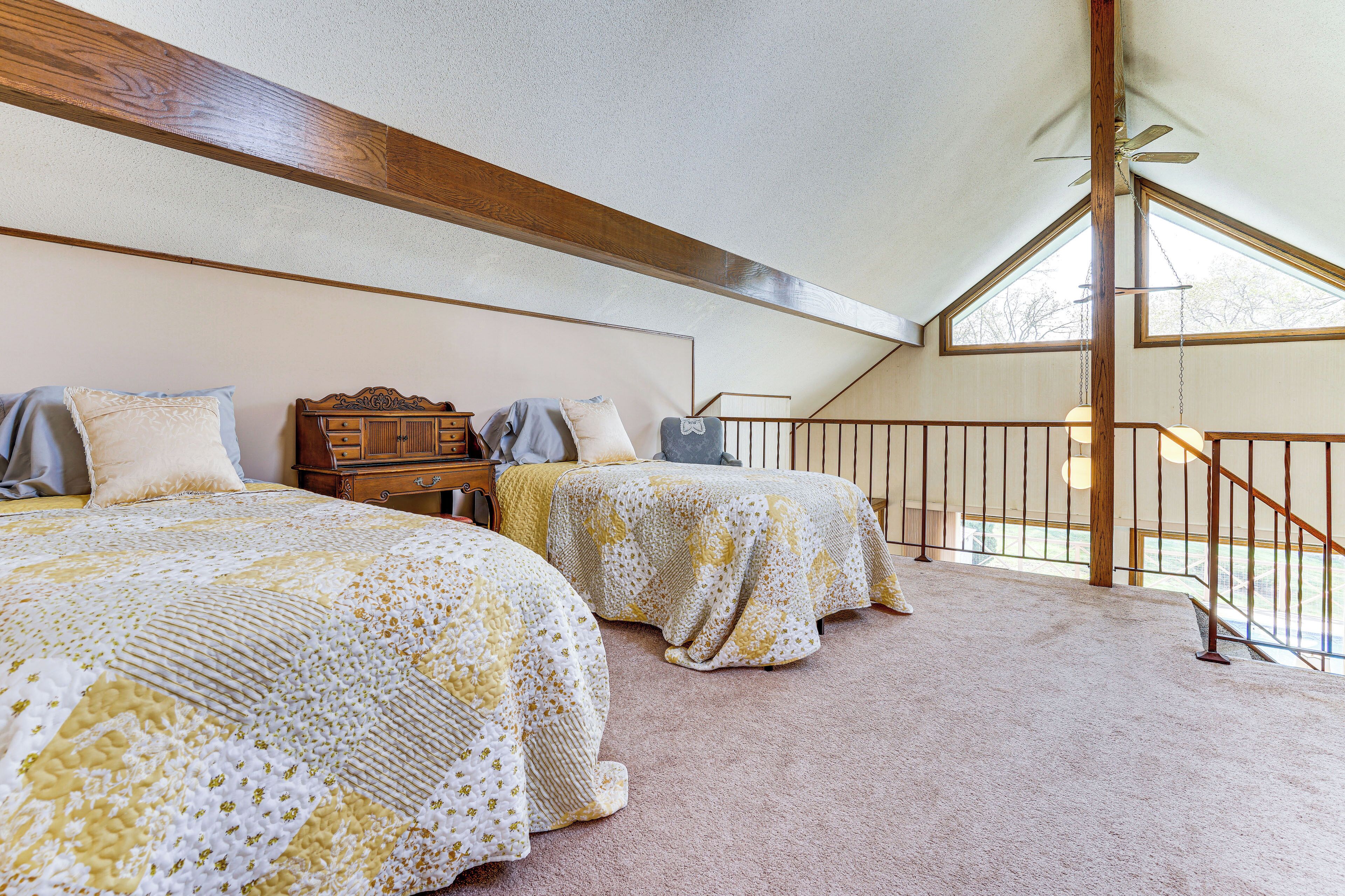 A bedroom with two beds, a wooden headboard, a dresser, and a balcony with a railing.