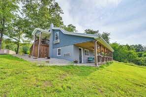 A two-story house with a covered porch, a wooden deck, and a stone pathway leading to the entrance. - 6 Mi to Lake Liberty: Pet-friendly Home w/ Yard (Liberty)